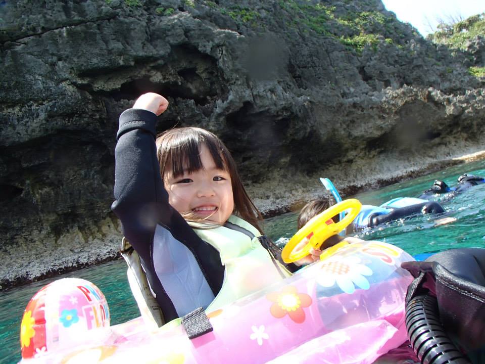 沖縄の青の洞窟で浮き輪で泳ぐ子ども