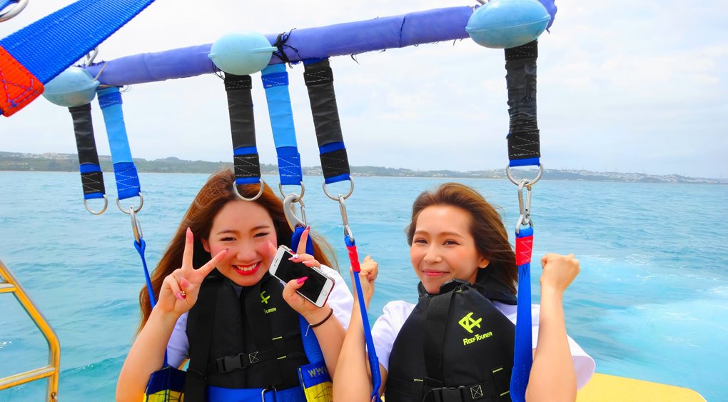 沖縄の海でパラセーリングを楽しむグループ
