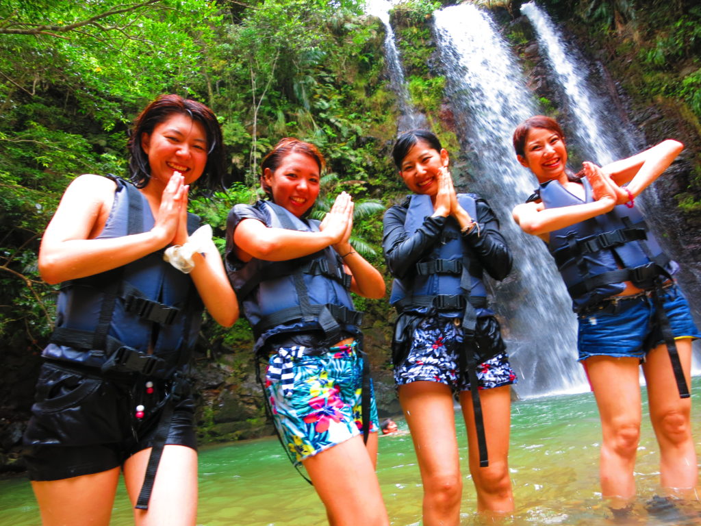 沖縄の名護でリバートレッキングツアーで滝をバックに記念撮影