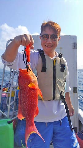 赤い魚を釣り上げる男性