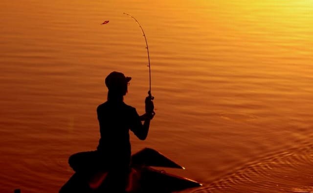 夕日の中で釣りをする女性