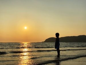 ビーチで夕日を眺める人