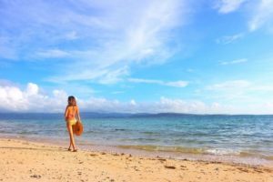 宮古島の9月のビーチを散策する水着の女性